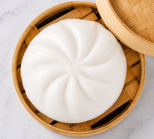 Jumbo Asado Siopao served in an open bamboo steamer basket.