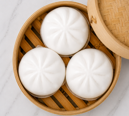 Mini Asado Siopao served in an open bamboo steamer basket.